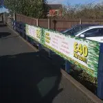 Temporary printed promotional banner secured to a fence